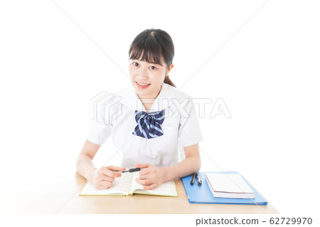 Female student in uniform studying at desk Female student in uniform studying at desk 62729970