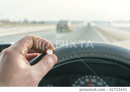 driver hand holding of pill while driving on the highway 62733433