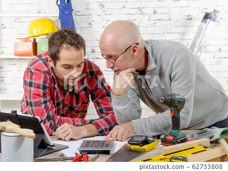 two technicians read plan in the workshop 62733808