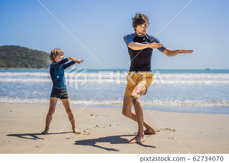 Father or instructor teaching his son how to surf in the sea on vacation or holiday. Travel and Father or instructor teaching his son how to surf in the sea on vacation or holiday. Travel and 62734070