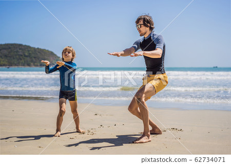 Father or instructor teaching his son how to surf in the sea on vacation or holiday. Travel and Father or instructor teaching his son how to surf in the sea on vacation or holiday. Travel and 62734071