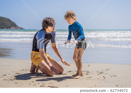 Father or instructor teaching his son how to surf in the sea on vacation or holiday. Travel and Father or instructor teaching his son how to surf in the sea on vacation or holiday. Travel and 62734072