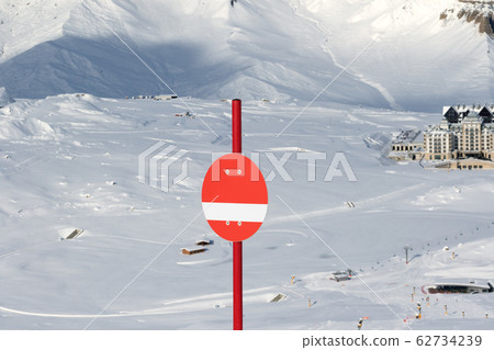 Sunlit red marker on snowy ski slope in high 62734239