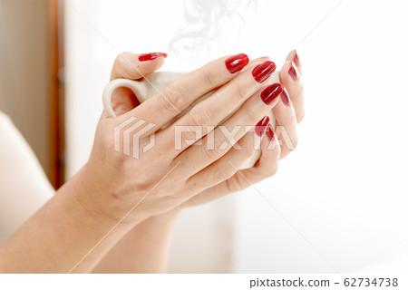 close-up of the hands of a young woman with a cup 62734738