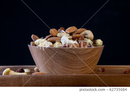 View of white bowl full of variety of nuts on black background View of white bowl full of variety of nuts on black background 62735084