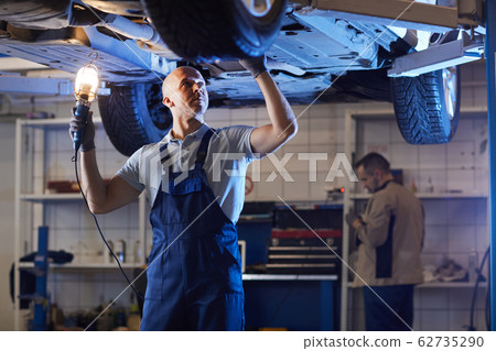 Auto Mechanic Inspecting Car on Lift 62735290