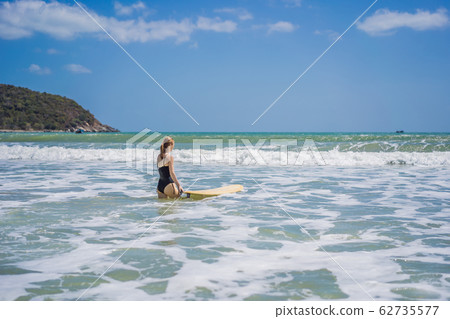 Beautiful young woman ride wave. Sporty surfer woman surfing on the background of blue sky, clouds Beautiful young woman ride wave. Sporty surfer woman surfing on the background of blue sky, clouds 62735577
