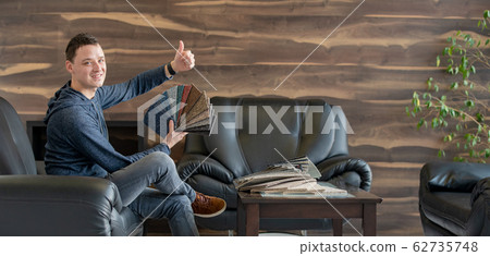 The man selects a new cover for the sofa from the color card sampler 62735748