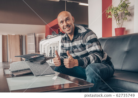 The man selects a new cover for the sofa from the color card sampler The man selects a new cover for the sofa from the color card sampler 62735749