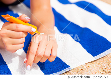 Young woman is lying on striped towel on the sand Young woman is lying on striped towel on the sand 62735974