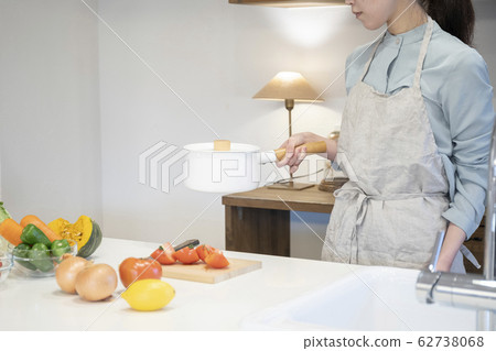 Hand of a young woman holding a pot in the kitchen Hand of a young woman holding a pot in the kitchen 62738068