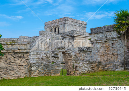 Ruins of ancient Tulum. Architecture of ancient maya. View with temple and other old buildings, houses. Blue sky and lush greenery of nature. travel photo. Wallpaper or background. Yucatan. Ruins of ancient Tulum. Architecture of ancient maya. View with temple and other old buildings, houses. Blue sky and lush greenery of nature. travel photo. Wallpaper or background. Yucatan. 62739645