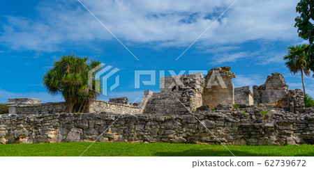 Ruins of ancient Tulum. Architecture of ancient maya. View with temple and other old buildings, houses. Blue sky and lush greenery of nature. travel photo. Wallpaper or background. Yucatan. 62739672