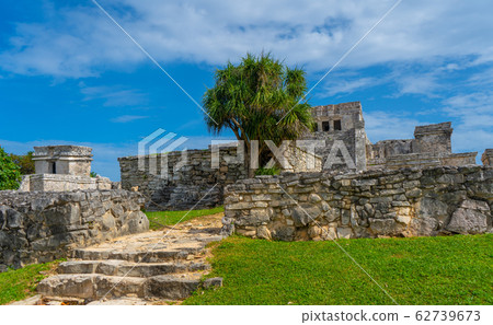 Ruins of ancient Tulum. Architecture of ancient maya. View with temple and other old buildings, houses. Blue sky and lush greenery of nature. travel photo. Wallpaper or background. Yucatan. 62739673