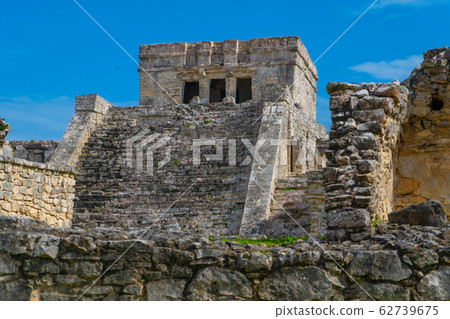 Ruins of ancient Tulum. Architecture of ancient maya. View with temple and other old buildings, houses. Blue sky and lush greenery of nature. travel photo. Wallpaper or background. Yucatan. 62739675