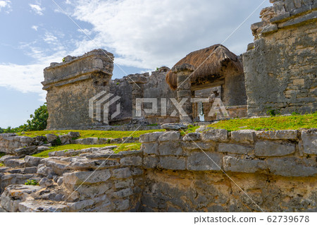 Ruins of ancient Tulum. Architecture of ancient maya. View with temple and other old buildings, houses. Blue sky and lush greenery of nature. travel photo. Wallpaper or background. Yucatan. Ruins of ancient Tulum. Architecture of ancient maya. View with temple and other old buildings, houses. Blue sky and lush greenery of nature. travel photo. Wallpaper or background. Yucatan. 62739678