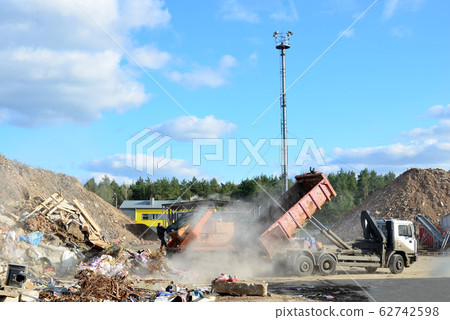 Garbage truck unloads construction waste from container at the landfill Garbage truck unloads construction waste from container at the landfill 62742598