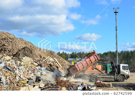 Garbage truck unloads construction waste from container at the landfill Garbage truck unloads construction waste from container at the landfill 62742599