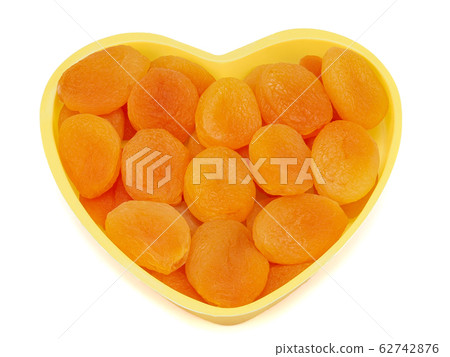 Heart shaped bowl of dried apricots isolated on white background Heart shaped bowl of dried apricots isolated on white background 62742876