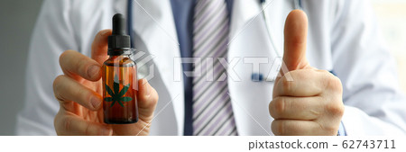 Male GP holding in hand cbd oil jar showing thumb up sign Male GP holding in hand cbd oil jar showing thumb up sign 62743711