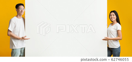 Positive asian man amd woman pointing at blank advertising board Positive asian man amd woman pointing at blank advertising board 62746055