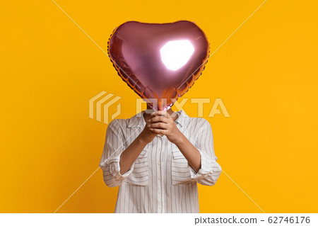 Unrecognizable Afro Woman Hiding Face Behind Heart Shaped Balloon Unrecognizable Afro Woman Hiding Face Behind Heart Shaped Balloon 62746176
