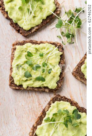 Vegetarian snacks with avocado and microgreen on white rustic wood board close up Vegetarian snacks with avocado and microgreen on white rustic wood board close up 62746202