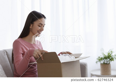 Glad woman open cardboard parcel, client feels satisfied 62746324