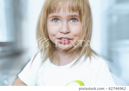 Portrait of charming little girl with big blue eyes and blond hair. Charming child is smiling and happy. Portrait of charming little girl with big blue eyes and blond hair. Charming child is smiling and happy. 62746962