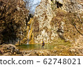Female hiker arrives and admires a waterfall with a beautiful puddle of water 62748021