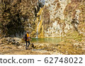 Female hiker arrives and admires a waterfall with a beautiful puddle of water 62748022