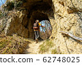 Female hiker walks through a natural mountain tunnel 62748025