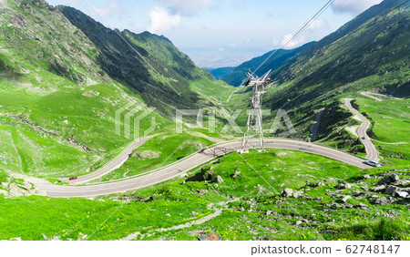 Top vew of winding road in mountains, with red car 62748147