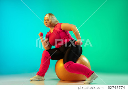 Young caucasian plus size female model's training on gradient green background Young caucasian plus size female model's training on gradient green background 62748774