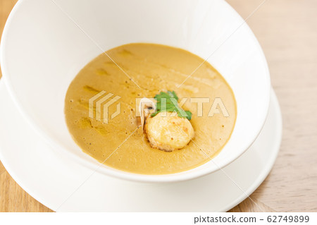 Fish soup in a white plate. Fish soup with vegetables, celery in a cup for the broth. Pike perch and salmon. Plate on wooden table. Restaurant menu 62749899