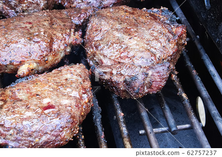 Closeup of BBQ steaks cooking on a grill Closeup of BBQ steaks cooking on a grill 62757237