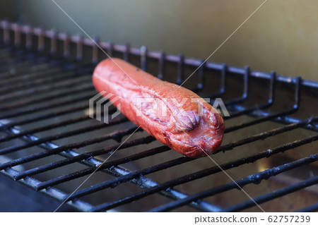 Front end view of a hotdog cooking on a grill 62757239