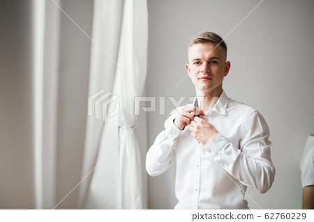 Grooms morning preparation. Handsome man getting dressed and preparing for the wedding Grooms morning preparation. Handsome man getting dressed and preparing for the wedding 62760229