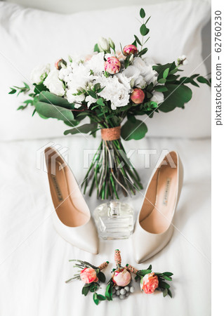 Pair of elegant and stylish bridal shoes with a bouquet with roses and other flowers Pair of elegant and stylish bridal shoes with a bouquet with roses and other flowers 62760230