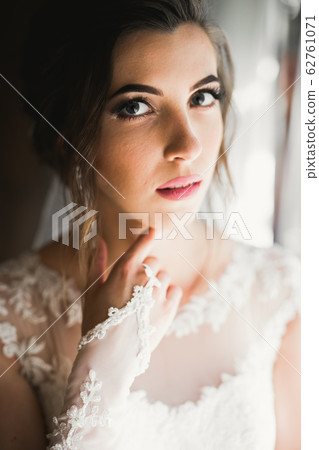 Gorgeous bride in robe posing and preparing for the wedding ceremony face in a room Gorgeous bride in robe posing and preparing for the wedding ceremony face in a room 62761071