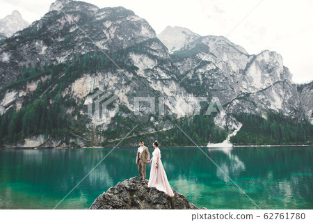 Young couple near lake Karersee, Italy. Holding hands at the stone at lake 62761780