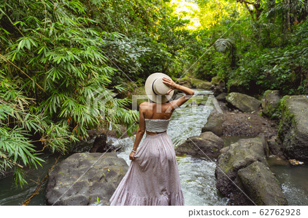 Woman standing by wild river in forest stock photo Woman standing by wild river in forest stock photo 62762928