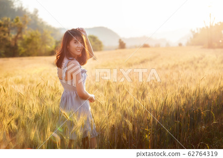 Beautiful and happy asian woman enjoying life in barley field Beautiful and happy asian woman enjoying life in barley field 62764319