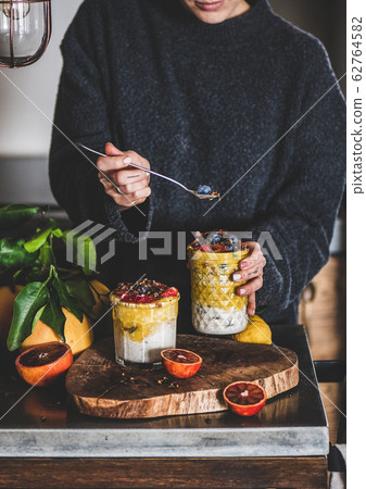 Woman eating muesli with mango smoothie, granola 62764582
