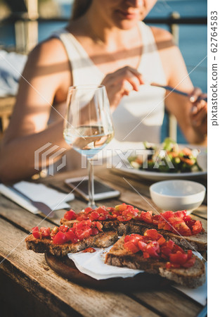 Young woman eating salad and brischetta in Italy Young woman eating salad and brischetta in Italy 62764583