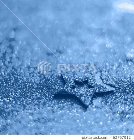 Christmas celebration. Abstract background for new year party. Patter of gold stars with lights, bokeh. Trendy blue and calm color. Glitter stars in monochrome color 62767912