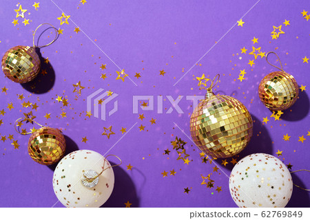 Christmas composition. Flat lay, top view. Disco ball bauble, star sparkles. Minimal New year party concept. Christmas white and gold decorations on violet background with copy space. 62769849