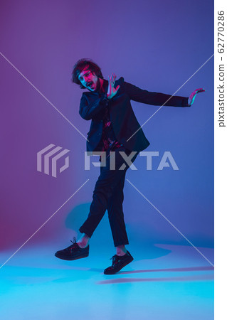 Young caucasian musician dancing in neon light 62770286