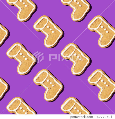 Christmas gingerbread pattern on violet background. Top view. Flat lay. Boot shapes cookies. New year and Christmas concept Christmas gingerbread pattern on violet background. Top view. Flat lay. Boot shapes cookies. New year and Christmas concept 62770501