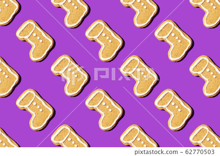 Christmas gingerbread pattern on violet background. Top view. Flat lay. Boot shapes cookies. New year and Christmas concept Christmas gingerbread pattern on violet background. Top view. Flat lay. Boot shapes cookies. New year and Christmas concept 62770503